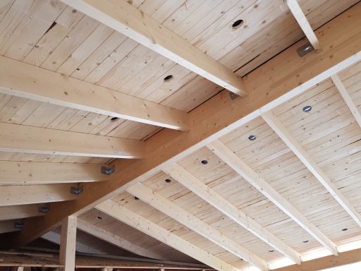 Takstolar av trä med synliga ljusinsatser och slutsystem i en byggnad.